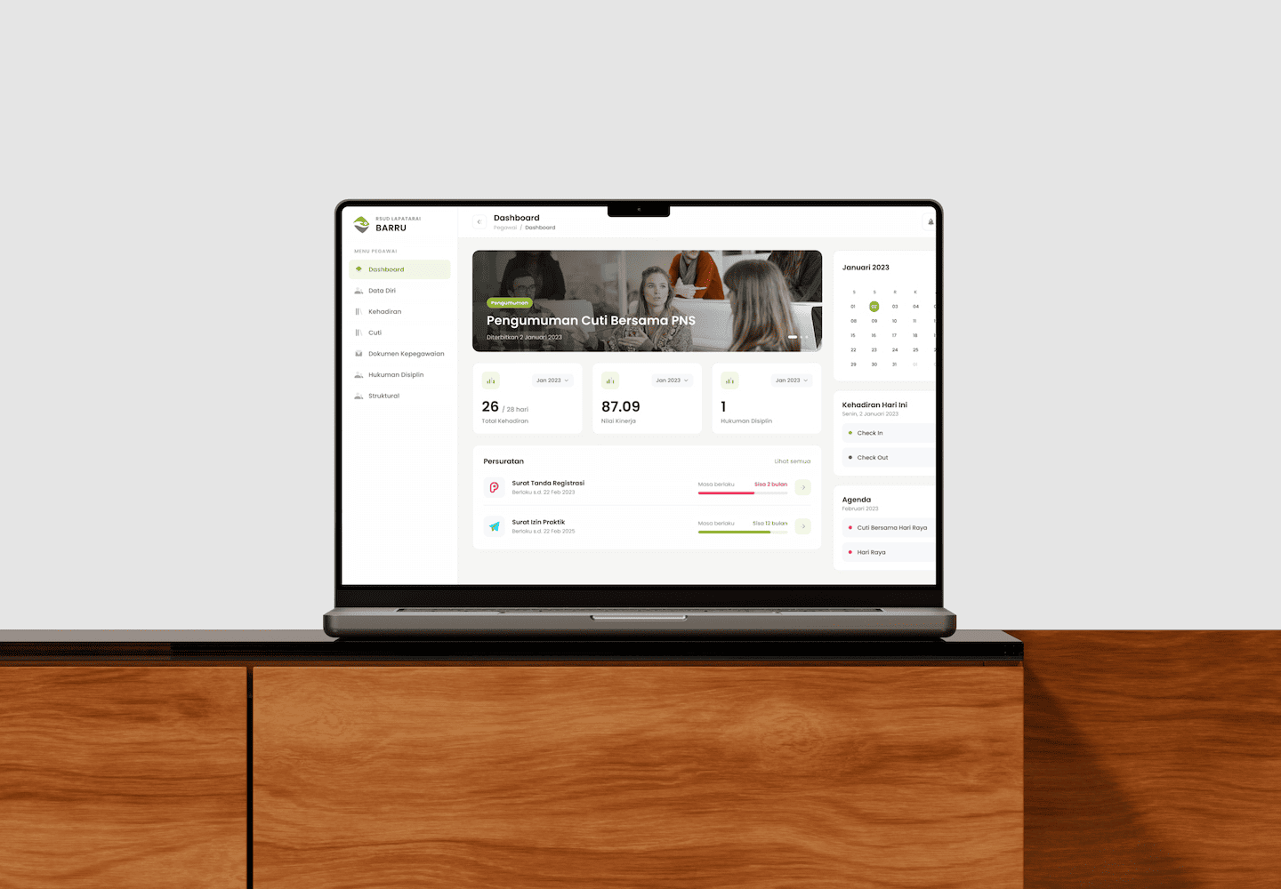 Laptop mockup on a wooden desk showing the SIMPEG dashboard for RSUD Lapatarai Barru with attendance and document stats.