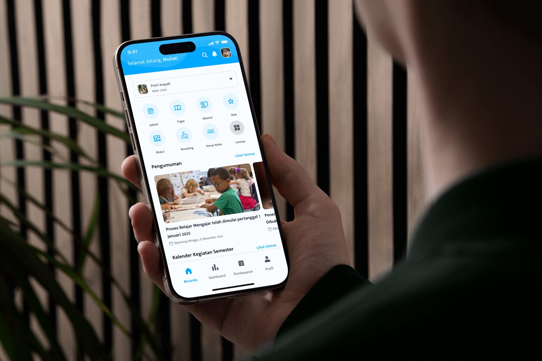 A hand holding a phone showing the Smart School parent home screen with the child’s assignments, attendance, and grades.