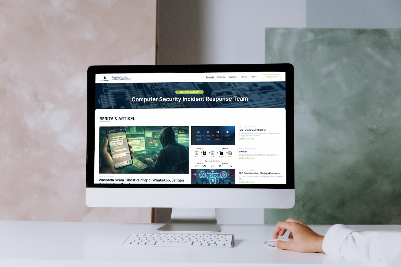 Monitor di meja kerja menampilkan beranda portal CSIRT dengan daftar berita dan artikel keamanan siber.